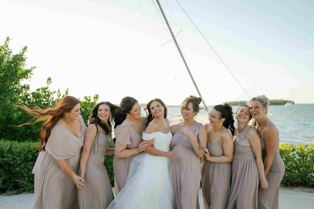 Bride laughing with her bridesmaids while getting ready in matching robes before the wedding.